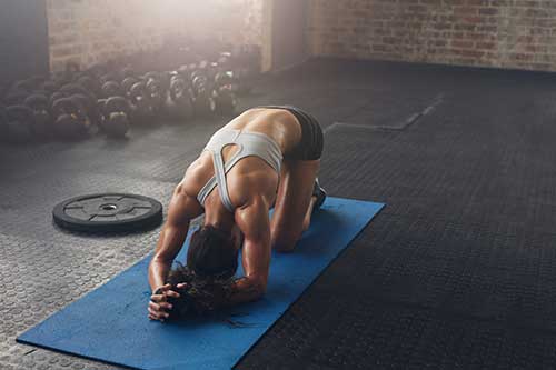 Mujer ejercitándose sobre colchoneta azul en gimnasio